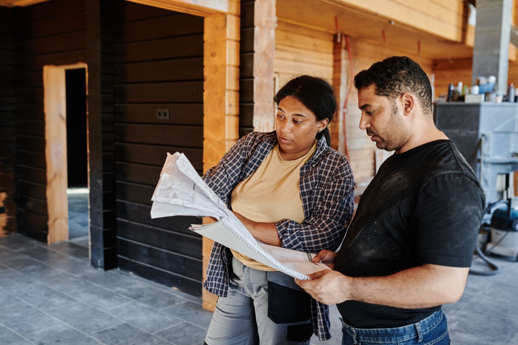 Twee bouwprofessionals bespreken tekeningen op de werkplek